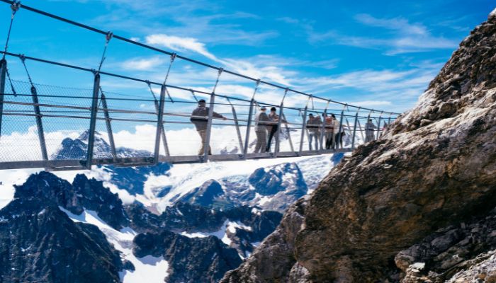 Thrilling moments on the Titlis Cliff Walk, suspended above the Swiss Alps, with panoramic views of majestic peaks
