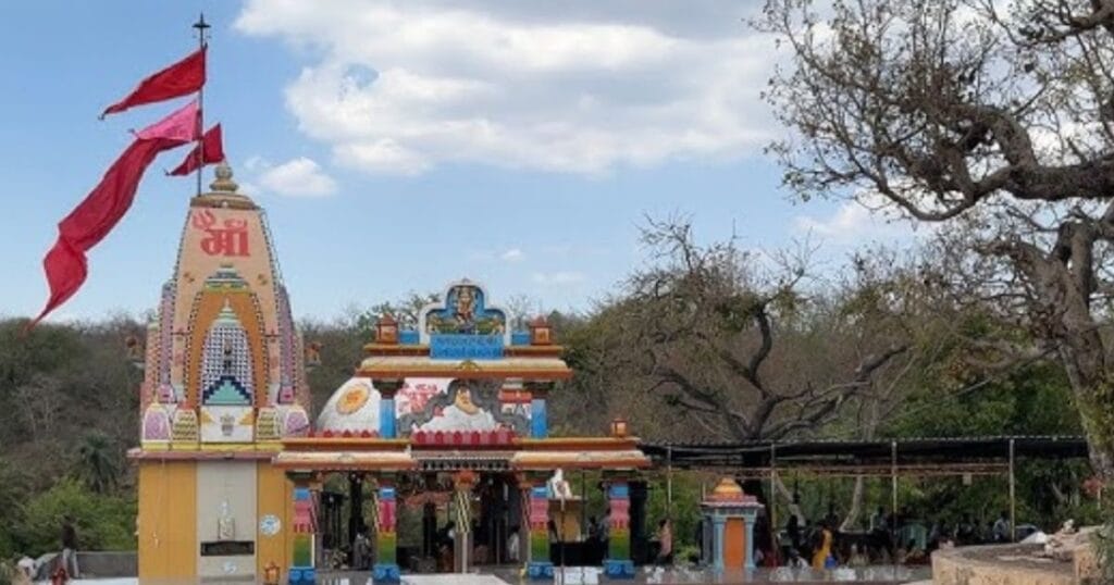 A vibrant Hindu temple with colorful carvings and flags stands amidst the trees of Gir.